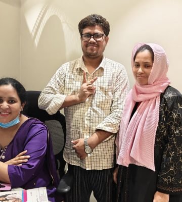 Smiling couple posing with a doctor in clinic.